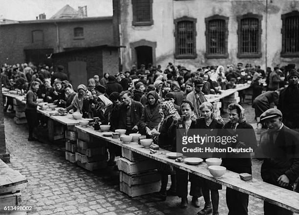 Some of the 3600 displaced Russian, Polish, French, Belgian, Spanish, Armenian, Algerian, Czech, Italian, and Dutch refugees eat a meal before being...