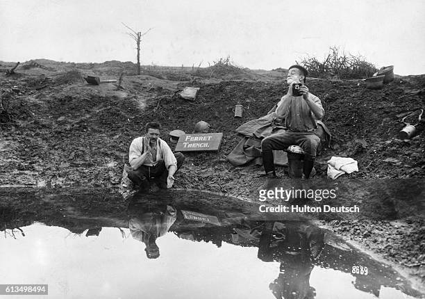Two German soldiers use the water collected in a shell hole or grenade hole to wash and shave themselves. | Location: Near Amiens, France.