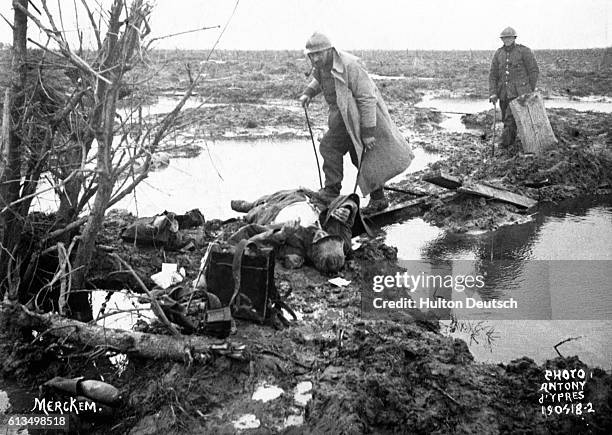 Two soldiers search the muddy battlefields of Ypres for lost or abandoned war materials or other valuables. In the first Battle of Ypres, October...