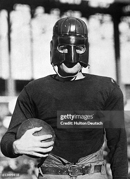"Hinkey" Haines, a player with the New York Football Giants, and former Pen State star, models a leather helmet designed to provide full facial...