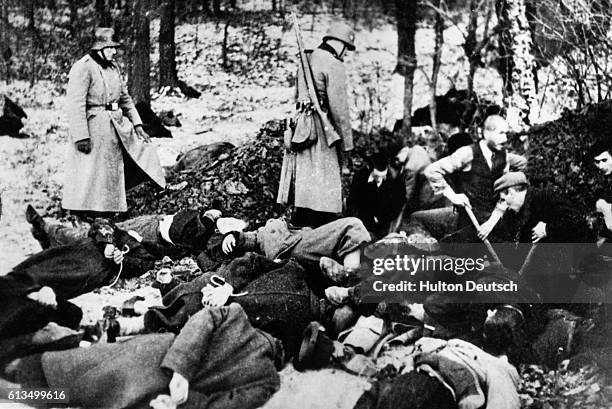 Nazi soldiers supervise as Polish prisoners dig a grave for fellow prisoners shot in a mass execution. When the task is done these prisoners will be...