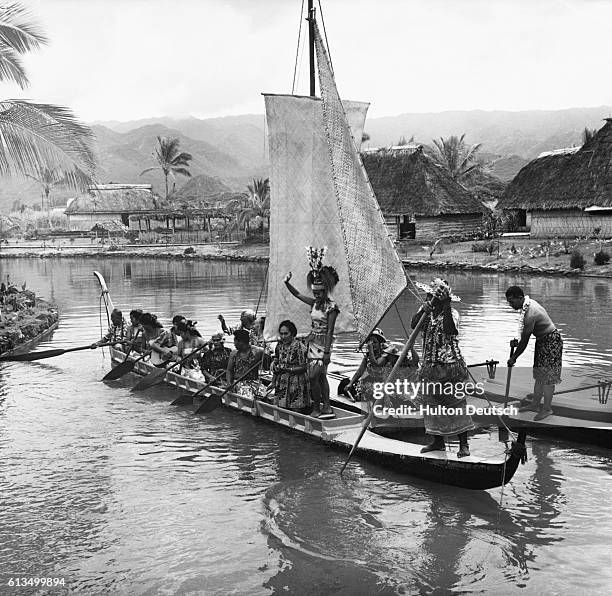 Western Samoan villagers sing and wave to visitors from their sailing canoe.