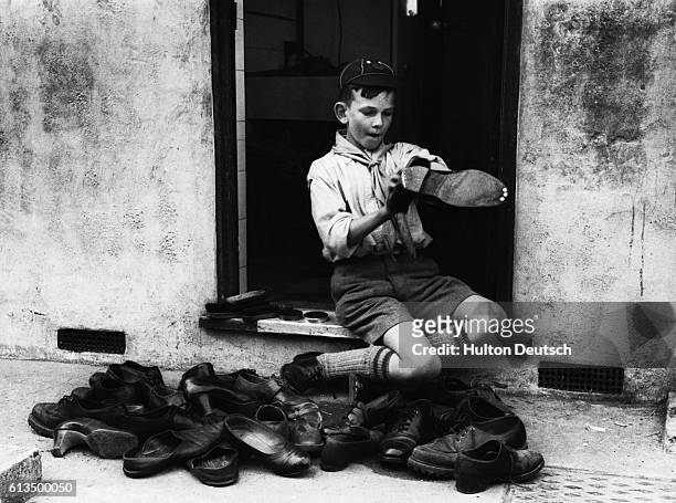 Young boy in London earning money by cleaning shoes for the first Scout and Cub Bob-A-Job week in May, 1949.