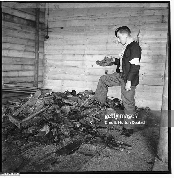 French soldier investigates the pile of footwear belonging to victims near the crematorium at Struthof Concentration Camp. | Location: Struthof Camp,...