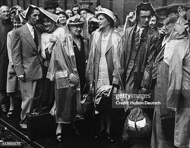 Unlucky travelers caught in a downpour at Waterloo Station during the holidays in July 1949. Queuing from left to right are Mr. And Mrs. Atkinson,...