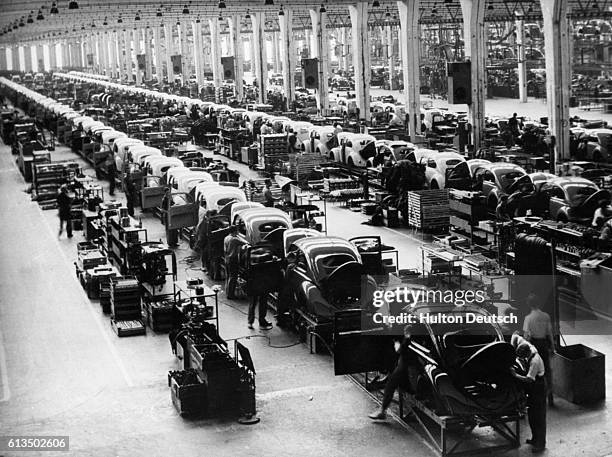 Rows of assembly lines of Volkswagen Beetles, designed by Ferdinand Porsche, at a factory in Germany.