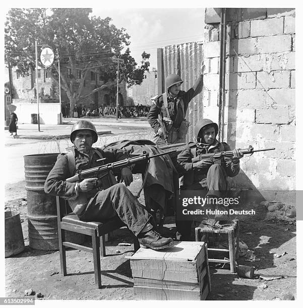 Three Israeli soldiers hold assault rifles by the side of a road in the Gaza Strip during the Suez Crisis.