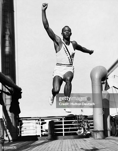 On board the S. S. Manhattan on the way to the 1936 Olympics in Berlin with the rest of the American team, Jesse Owens practises the long jump on the...