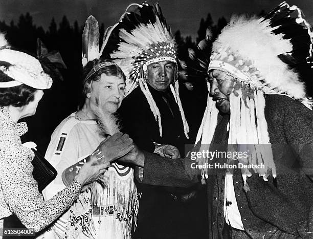 American author Helen Keller, wearing traditional Native American costume, receives an emblematic white plume from Stoney Indian Chief Walking...