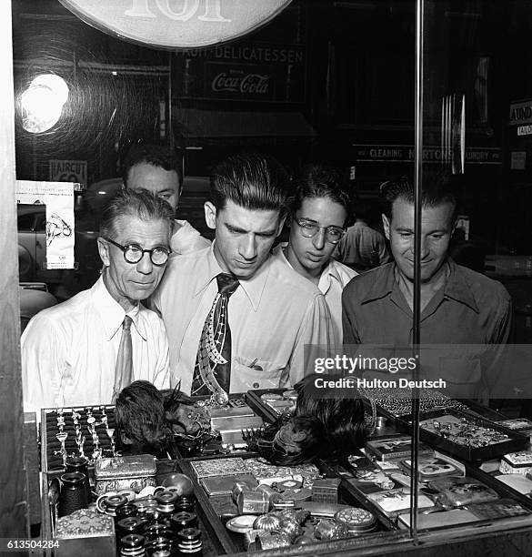 Passers-by are fascinated by a pair of shrunken Jivaro heads displayed with a collection of trinkets in a window of Rosenbergs' New York store.