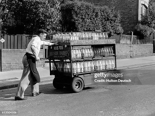 Photo shows: A milkman operating a hand-operated electric milk float at Muswell Hill, London.