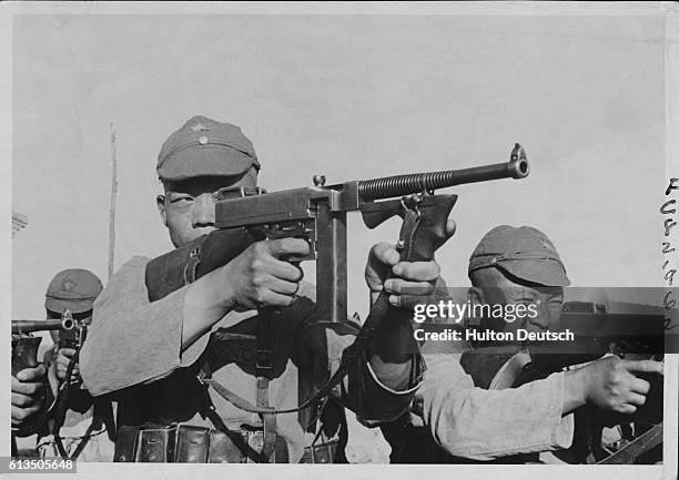 Their aim is deadly. Those slant eyes behind the sights of the machine guns are fixed on their target which is the Japanese attackers who are...