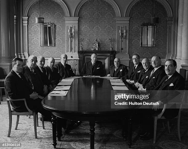 Eleven businessmen seated around a table at a meeting on the City of London.