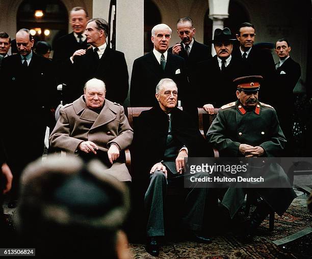 Soviet leader Stalin, American President Roosevelt and British Prime Minister Churchill seated together during the Yalta Conference, 1945. Behind...
