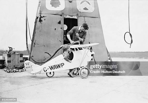 The young son of a director of Heston Aerodrome pulls up at a refueling station in a specially designed, replica, aircraft.