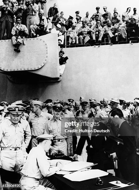 Gen. Douglas MacArthur, Supreme Allied Commander during formal surrender ceremonies on the USS Missouri in Toyko Bay, looks on as Japan signs the...