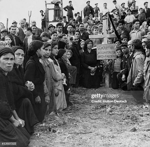 Crowd of Italians mourn the death of sixteen people murdered by Nazis in the village of Rionero Sannitico. A cross bears a sign that states that the...