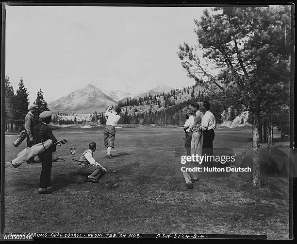 Golfers watch a companion tee off from hole 3 of the Banff Springs Golf Course.