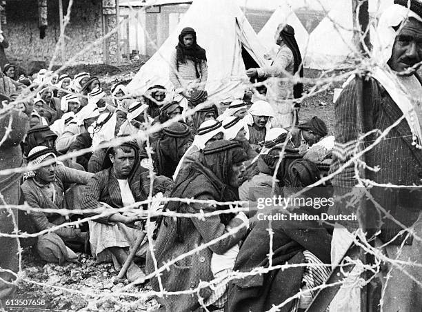 Arab prisoners of war behind barbed wire in a prison camp situated at Jenin, an area of Palestine known as the Triangle of Terror. The regime is...