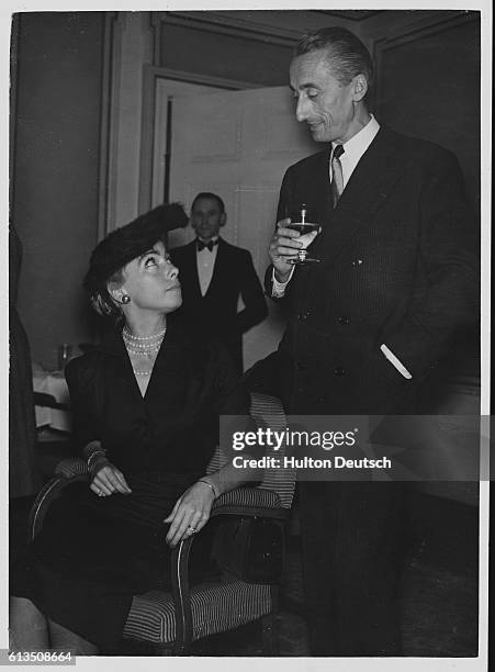 Jacques Cousteau the French oceanographer and underwater explorer who invented the Aqualung diving apparatus, talks to his wife at a party.