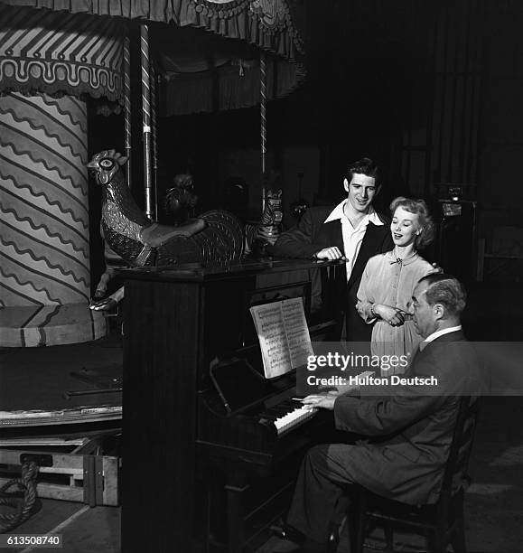 Richard Rodgers the American composer playing the piano to accompany two singers at a rehearsal for his musical Carousel, running in London.