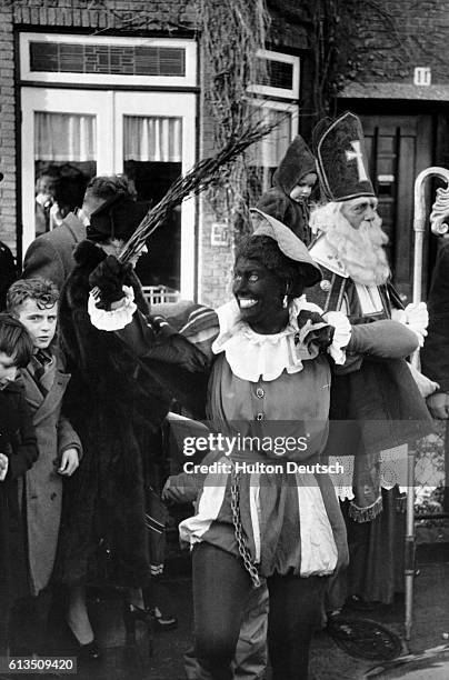 Saint Nicholas, the Dutch Santa Claus and his assistant Black Peter visit a Dutch town before his Feast of December 6. Black Peter carries a birch...