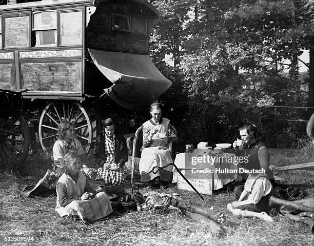 Women and children take morning tea outside a caravan parked in a field owed Sir Charles and Lady Sybil Grant, close to the Epsom Downs racecourse.