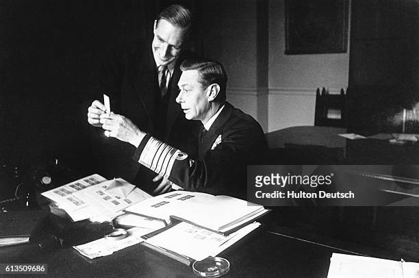 King George VI examining stamps from his collection.
