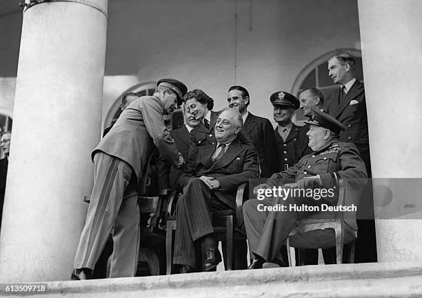 The Russian leader, Joseph Stalin, shakes hands with Miss Sarah Churchill whose father, Sir Winston Churchill the British Prime Minister, sits beside...