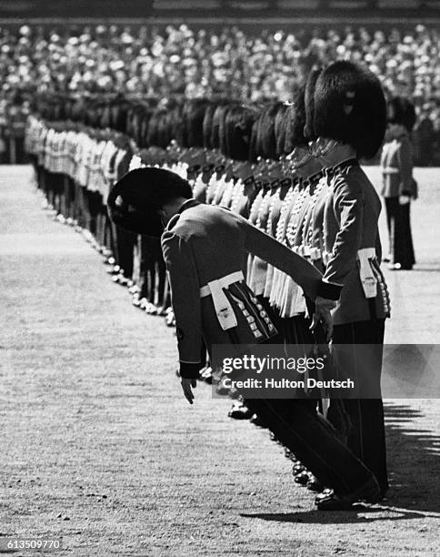 British guardsman falls to the ground in 1957's Trooping the Colour ceremony, from heat exhaustion, in Horse Guards Parade, London, England.