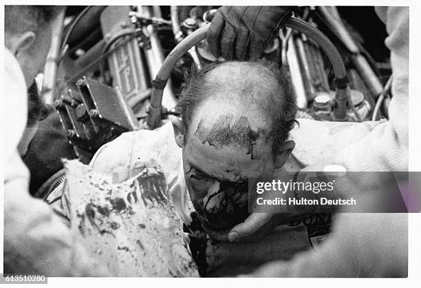 Injured British racing driver Stirling Moss is removed from the car he has crashed during a race at Goodwood.