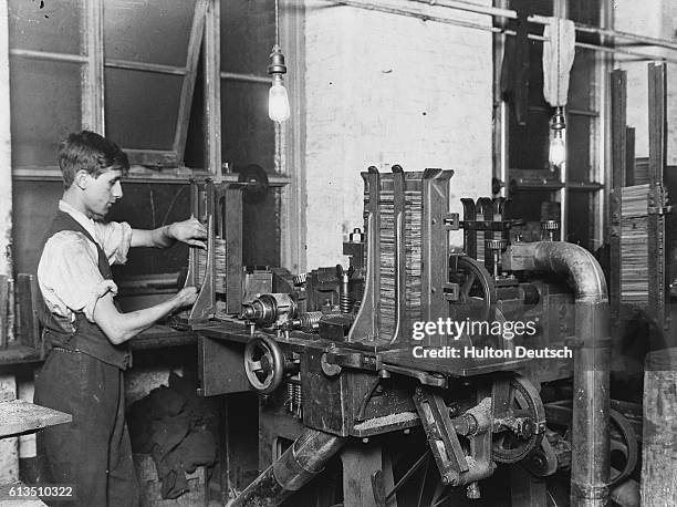 Young man operates a machine for grooving cedar slats in a pencil making factory.