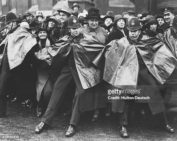 Police form a barrier, by holding hands, as they try to keep back the crowd attempting to enter Westminster Abbey for the funeral of Queen Alexandra...