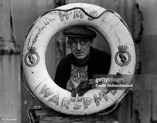 The keeper of the H.M.S. Warspite, a ship used by Britain in WWI and WWII, and the ship's cat 'Stripey', before they were both transferred to another...