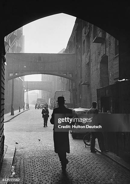 Pedestrians walk under the arches of London's Wapping High Street in 1949.