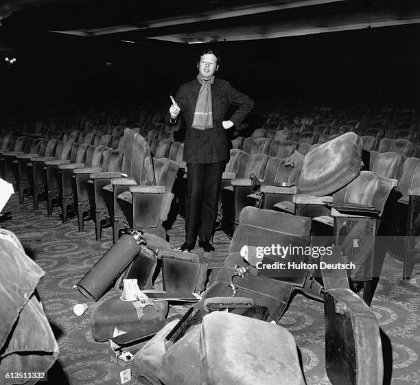 The music producer and manager of The Beatles, Brian Epstein, stands amidst broken seating at the Saville Theatre in London, 1960s.