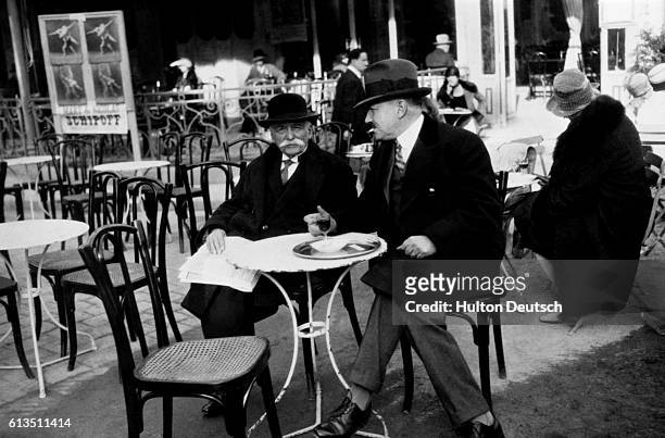 The French Chef, Auguste Escoffier, sits in front of a Paris cafe with a friend, ca. 1925.