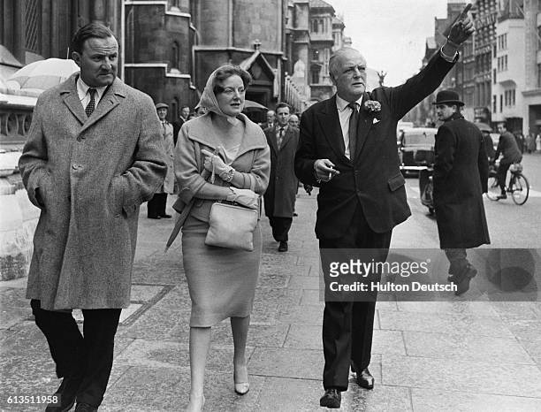 The Conservative politician and journalist Randolph Churchill walks along the street with his wife Diana.