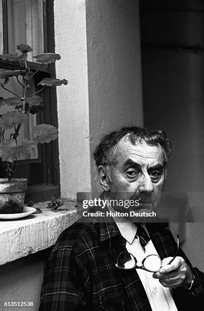 Man Ray, an American photographer, filmmaker, and painter sits outside a house. Man Ray was a major figure in the development of Modernism and...