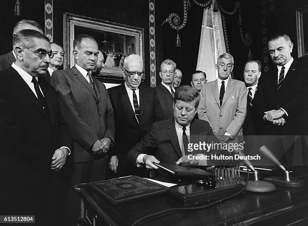 President Kennedy, surrounded by U.S. Cabinet officials and senators, prepares to sign the Nuclear Test Ban Treaty with the Soviet Union in 1963.