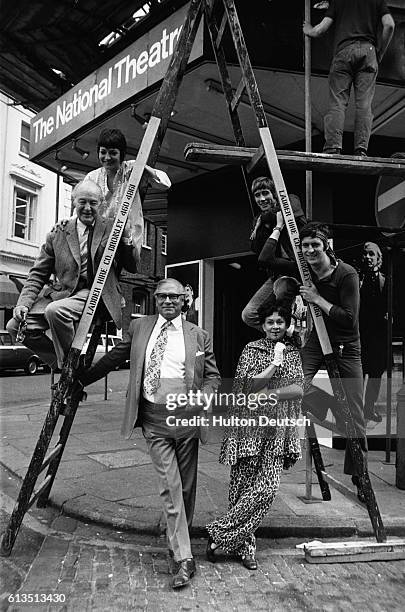 Standing on a ladder outside Cambridge Theatre, the members of the cast of the 'Merchant of Venice', with Sir Lawrence Olivier and his wife Joan...