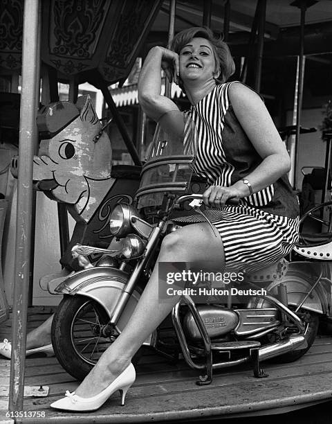 British actress Liz Fraser has a ride on a merry-go-round at the Battersea Fun Fair, London, 1966.