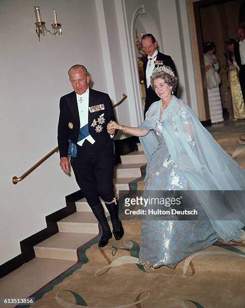 Paul I, King of the Hellenic Republic of Greece, escorts his wife, Queen Fredericka, as they descend a flight of steps.