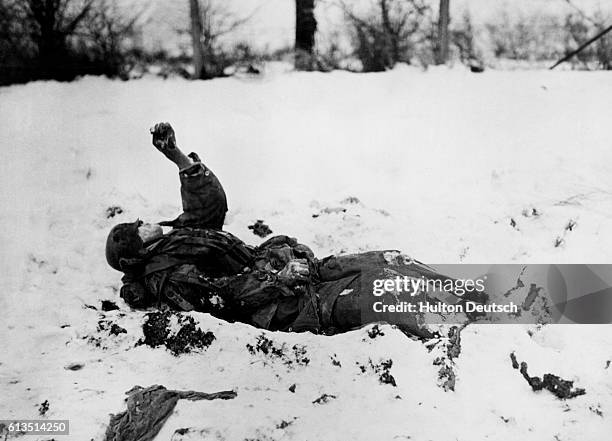 The frozen body of a German Nazi soldier, a victim of American bombing, lies in the snow where he fell in Belgium during World War II. | Location:...
