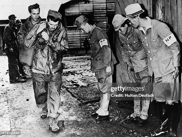 Former prison camp guards at OFUNA, a harsh and cruel Japanese prisoner of war camp, bow to their former prisoners as the liberated Allied prisoners...