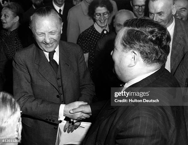 Professor Carl Schmidt congratulates the new Chancellor Konrad Adenauer with a handshake.