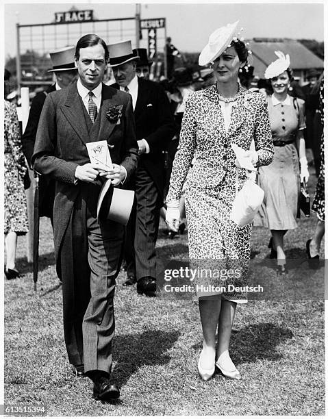 King Edward VIII and the Duchess of Windsor walk through the racing paddocks on the day of a big race.