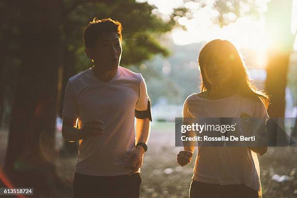 早朝に屋外で運動する日本のスポーツカップル - asian woman smiling sunrise ストックフォトと画像