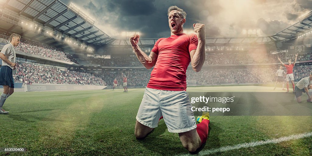 Soccer Player Kneeling on Pitch With Clenched Fists in Celebration