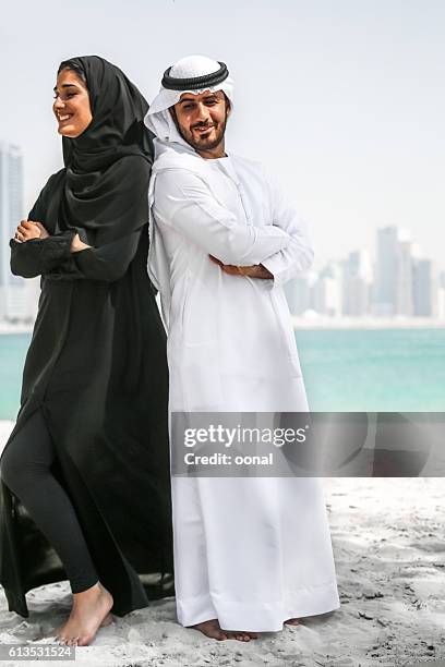 arab couple with traditional wear on the beach - muslim woman beach stock pictures, royalty-free photos & images